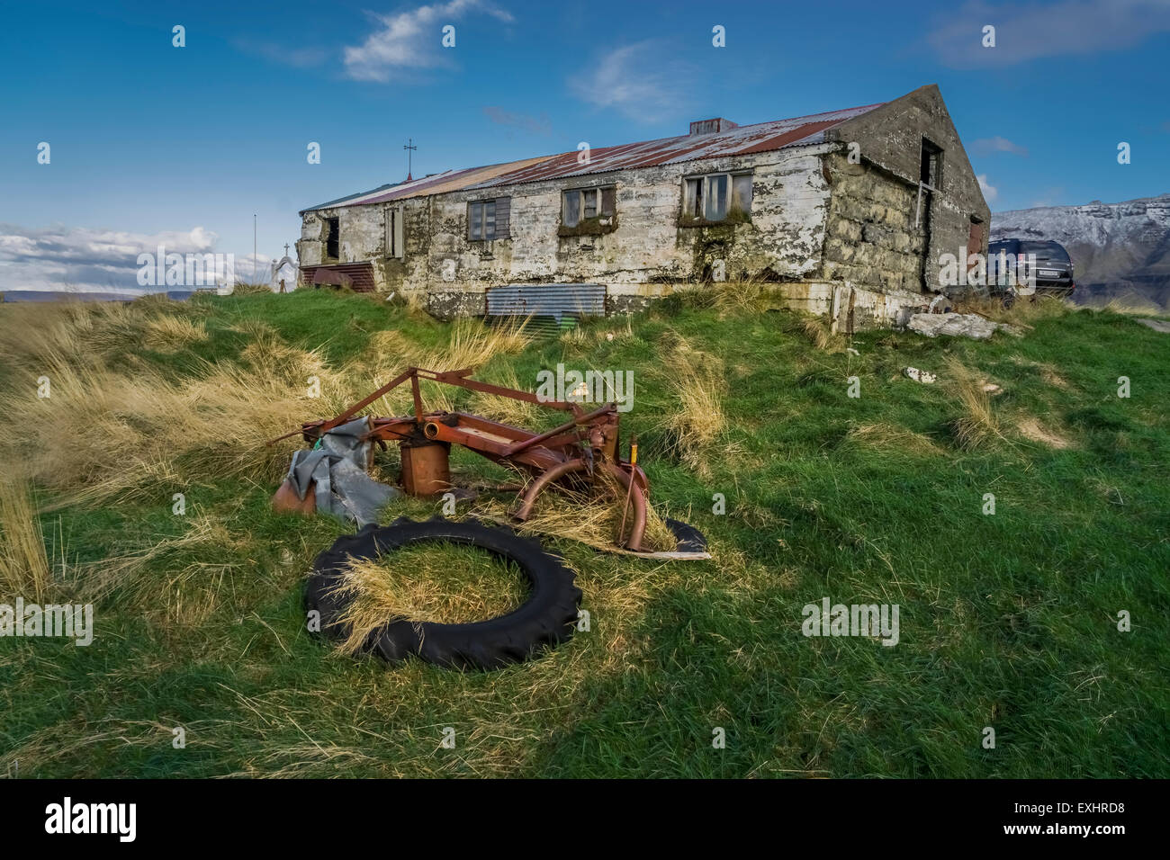 Alter Bauernhof mit rostigen Ausrüstung und Reifen, Kolbeinsstadur Farm, West-Island. Stockfoto