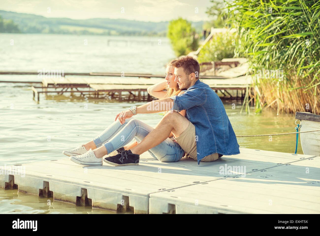 Paar in Liebe auf dem Pier, sitzen Stockfoto
