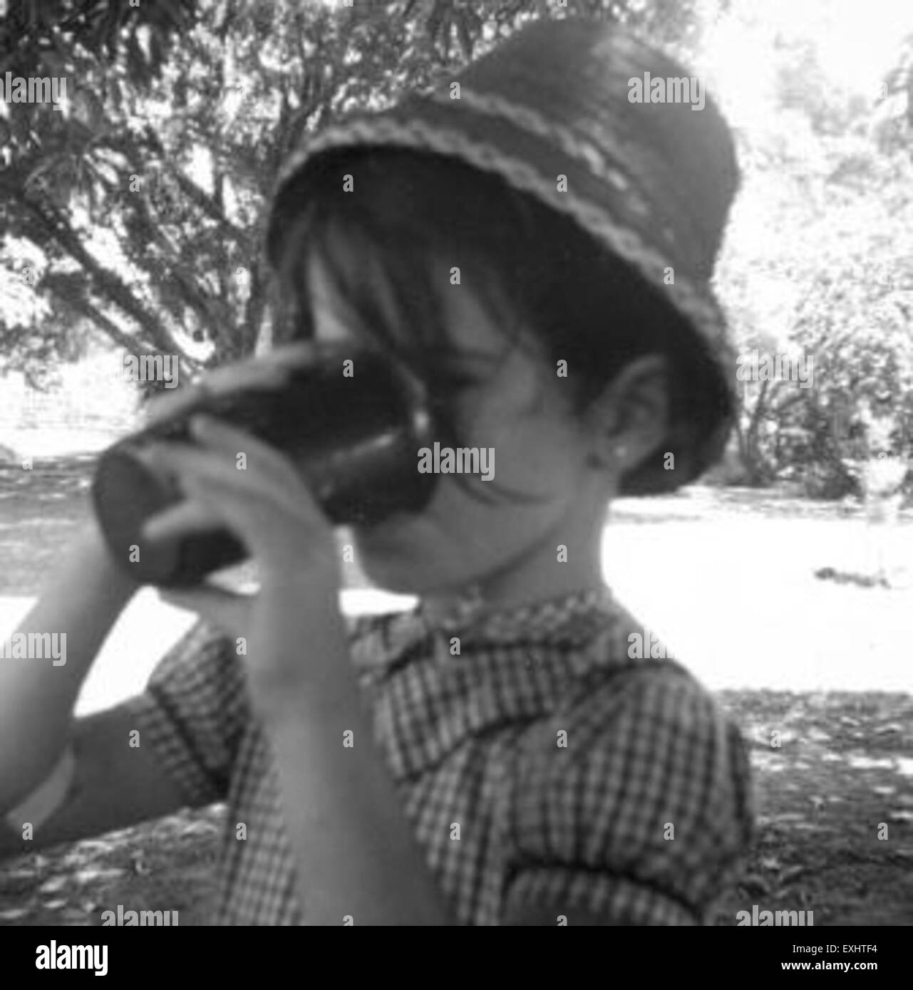 Dieses Bild von Vivian, der Kool-Aid trinkt, fängt einen Moment der lockeren Erfrischung ein. Die Szene zeigt den Alltag der Figur und spiegelt eine beliebte amerikanische Getränkekultur und ihre soziale Bedeutung wider. Stockfoto