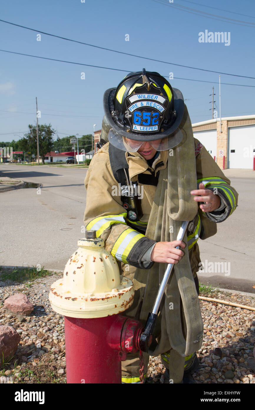 Weibliche Feuerwehrmann in ländlichen Freiwillige Feuerwehr mit Arbeitsmitteln. Stockfoto