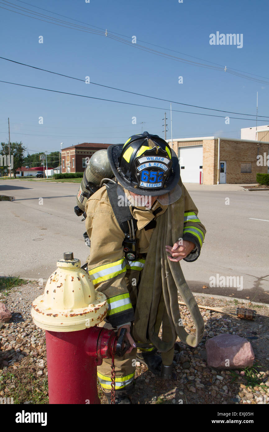 Weibliche Feuerwehrmann in ländlichen Freiwillige Feuerwehr mit Arbeitsmitteln. Stockfoto