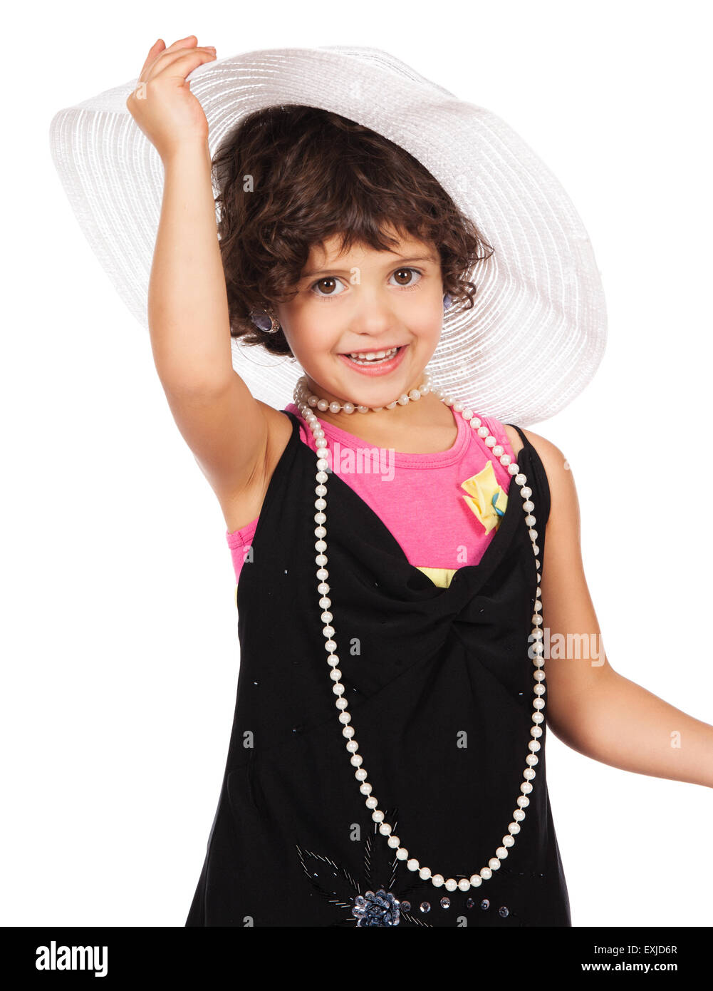 Entzückendes niedliche kaukasisches Mädchen spielt Kleid auf. Sie trägt ein schwarzes Kleid, weißen Hut, Ohrringe und Korallen hochhackige Schuhe. Stockfoto