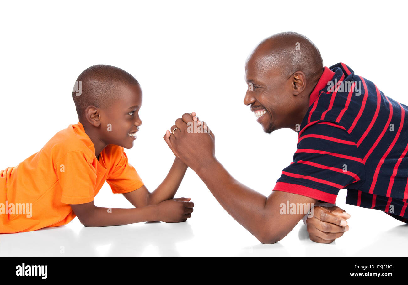 Niedlichen afrikanischen jungen hell orange T-shirt und Jeans dark Denim spielt Arm Wrestling mit seinem Vater. Stockfoto