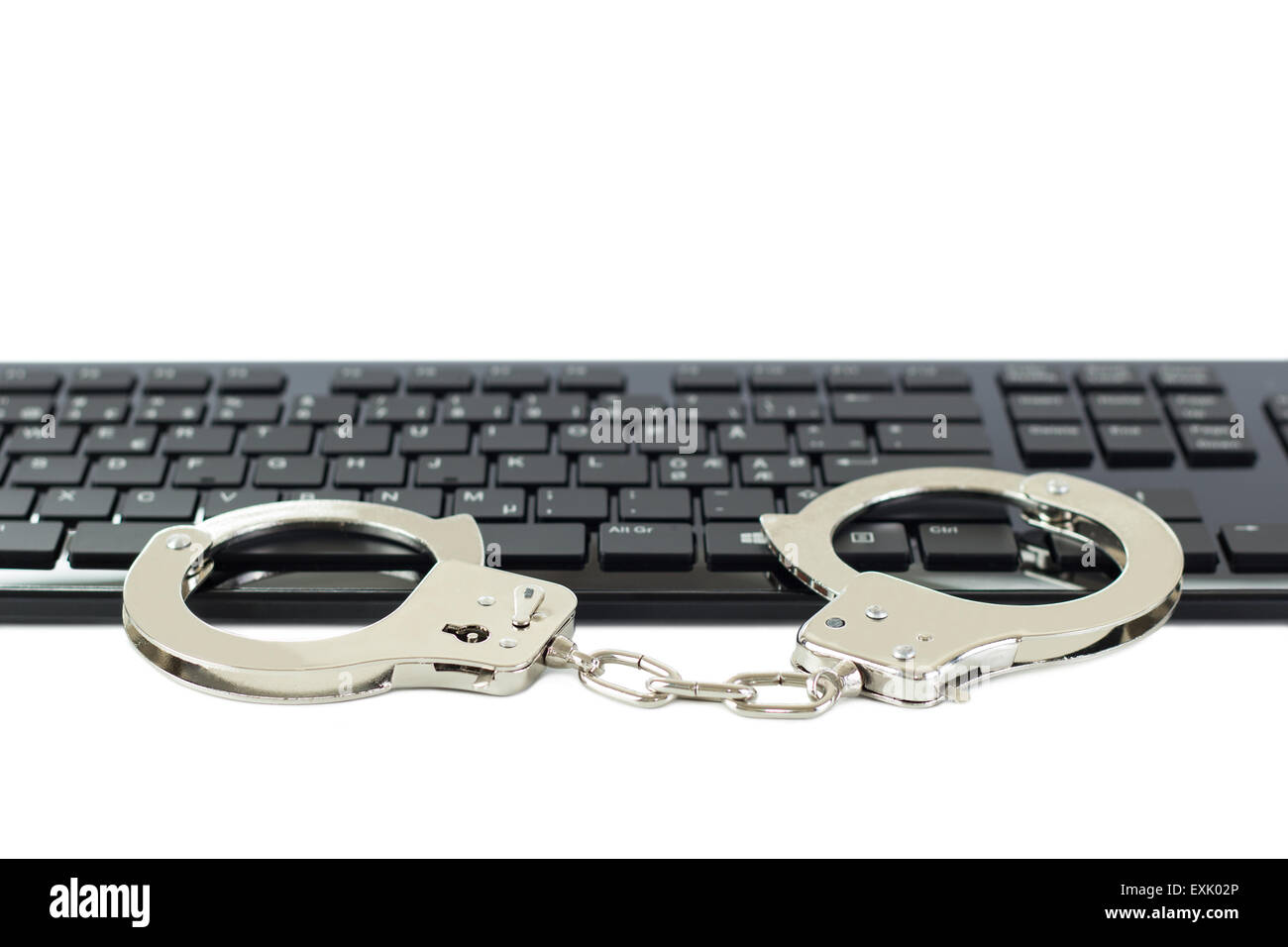 Metall-Handschellen auf einer Tastatur, isoliert auf weiss. Konzept-Foto von Computer, Internet & Cybercrime und Piraterie, hacking & Phishing. Stockfoto