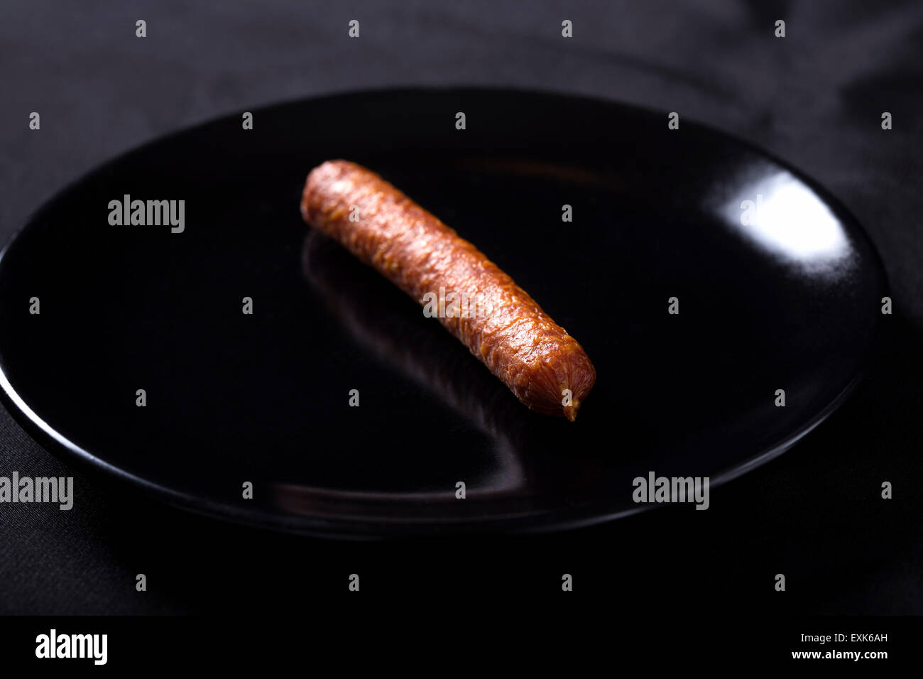 Eine dünne geräucherte Wurst auf dunkle Platte Stockfoto