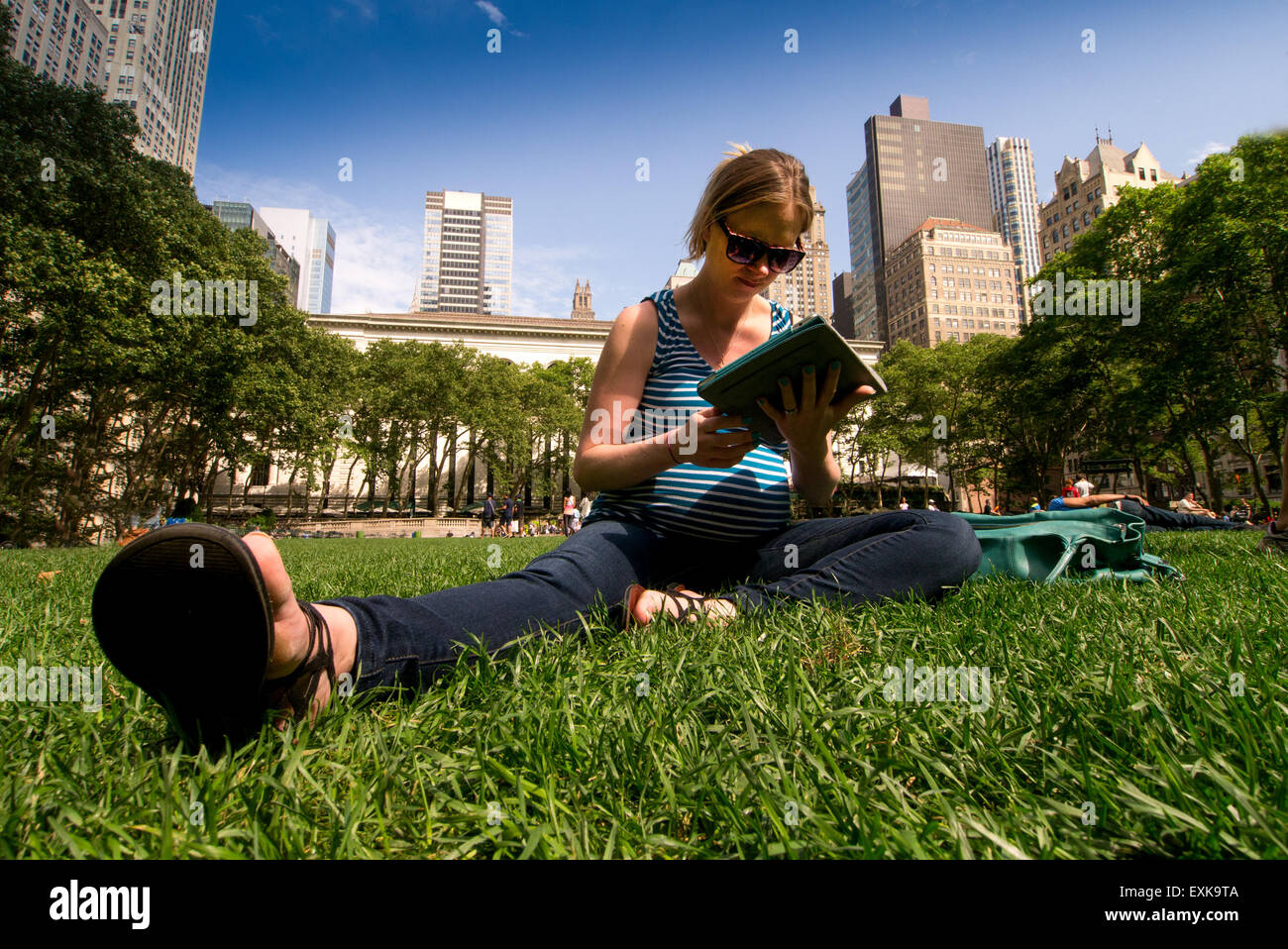 Junge schwangere Frau Recherche auf ihr Tablet im Bryant Park, New York City Stockfoto