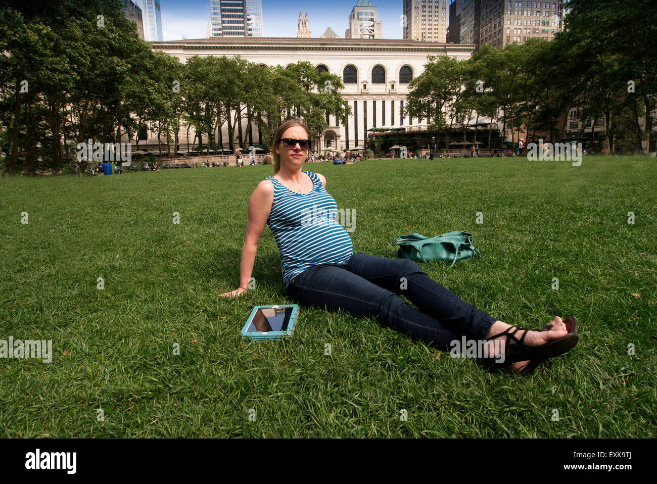 Junge schwangere Frau Recherche auf ihr Tablet im Bryant Park, New York City Stockfoto