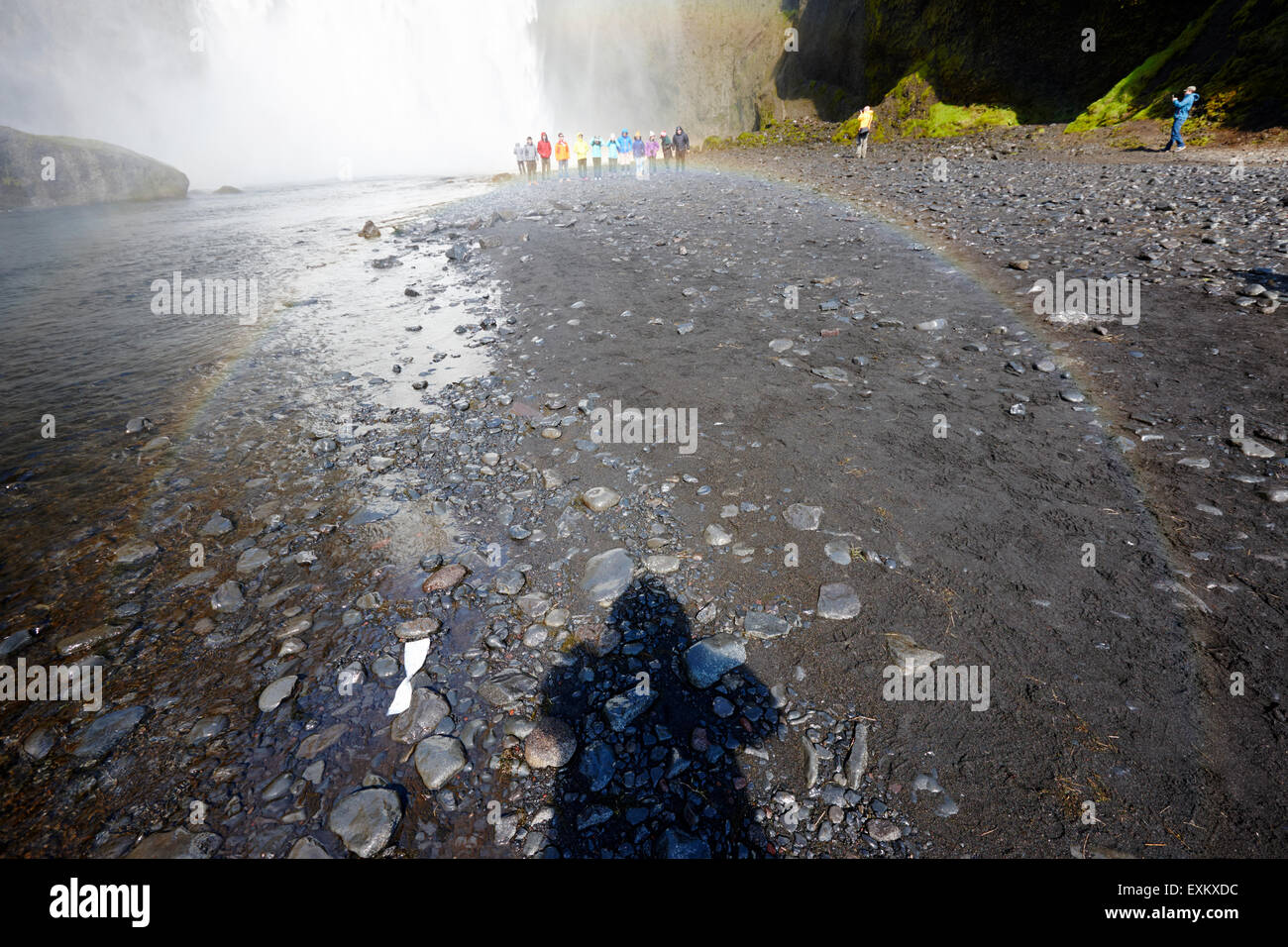 Schatten der touristischen und kreisförmigen Regenbogen Massen von Touristen am Skogafoss Wasserfall in Island Stockfoto