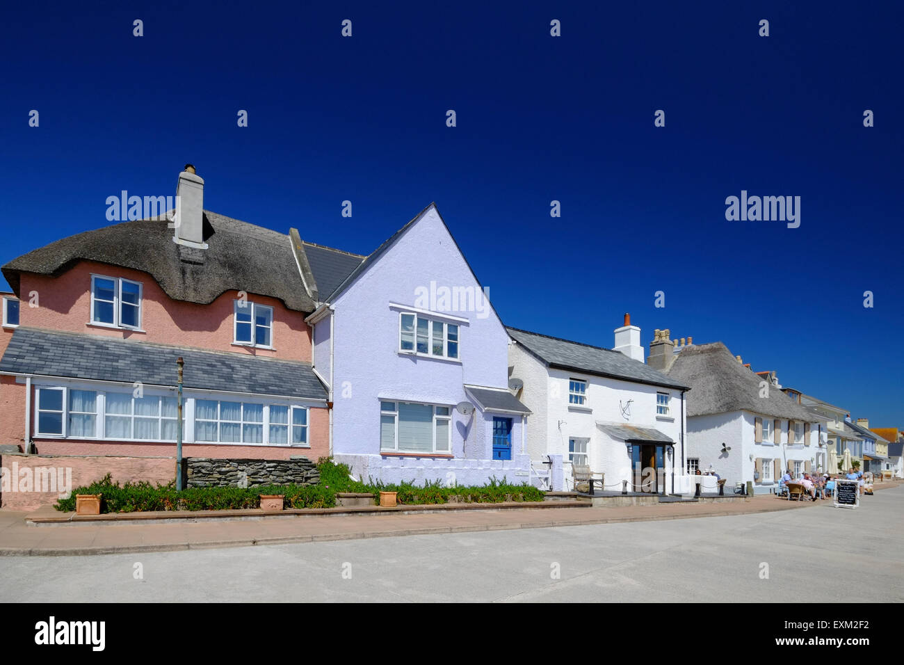 Torcross, Devon, UK.  Pastellfarben strohgedeckten Hütten und Häuser Gesicht am Strand bei Torcross in Devon. Stockfoto