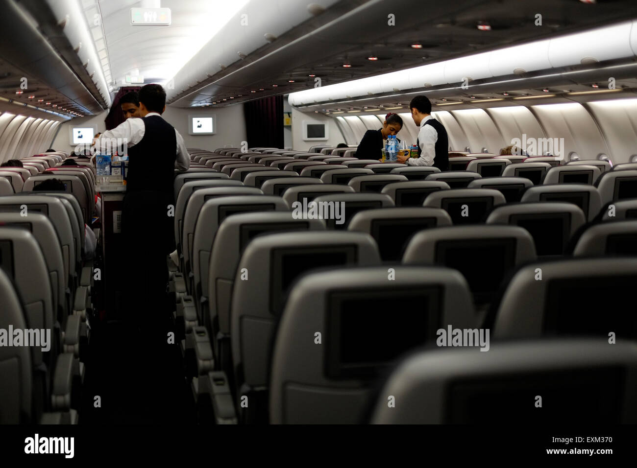 Crew serviert Erfrischungen für Passagiere in einer fast menschenleeren Economy-Kabine auf einem Qatar Airlines Flug von Jakarta nach doha Stockfoto