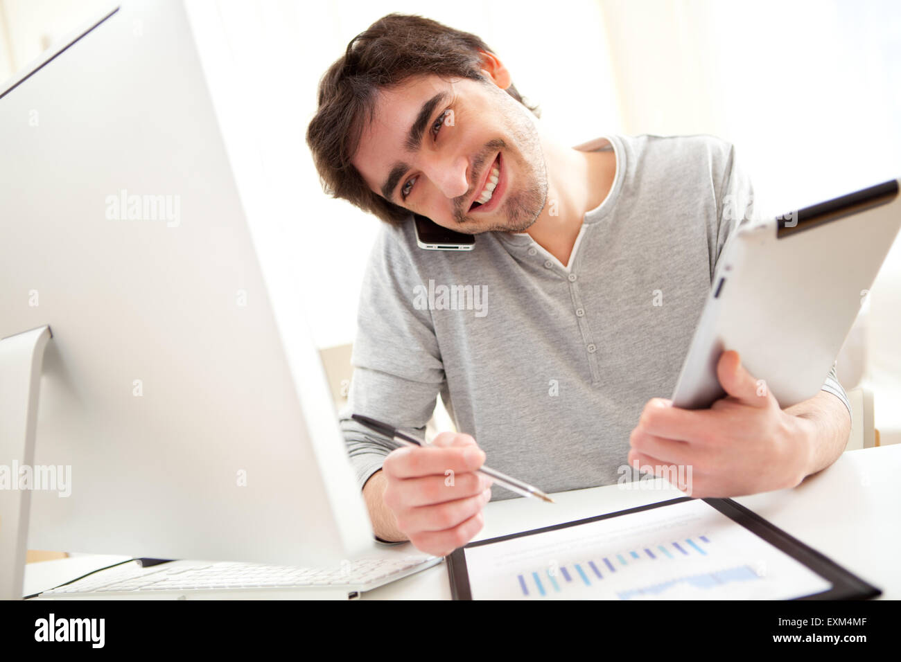 Blick auf eine junge Vielbeschäftigte Männer im Büro mit Tablet und smartphone Stockfoto