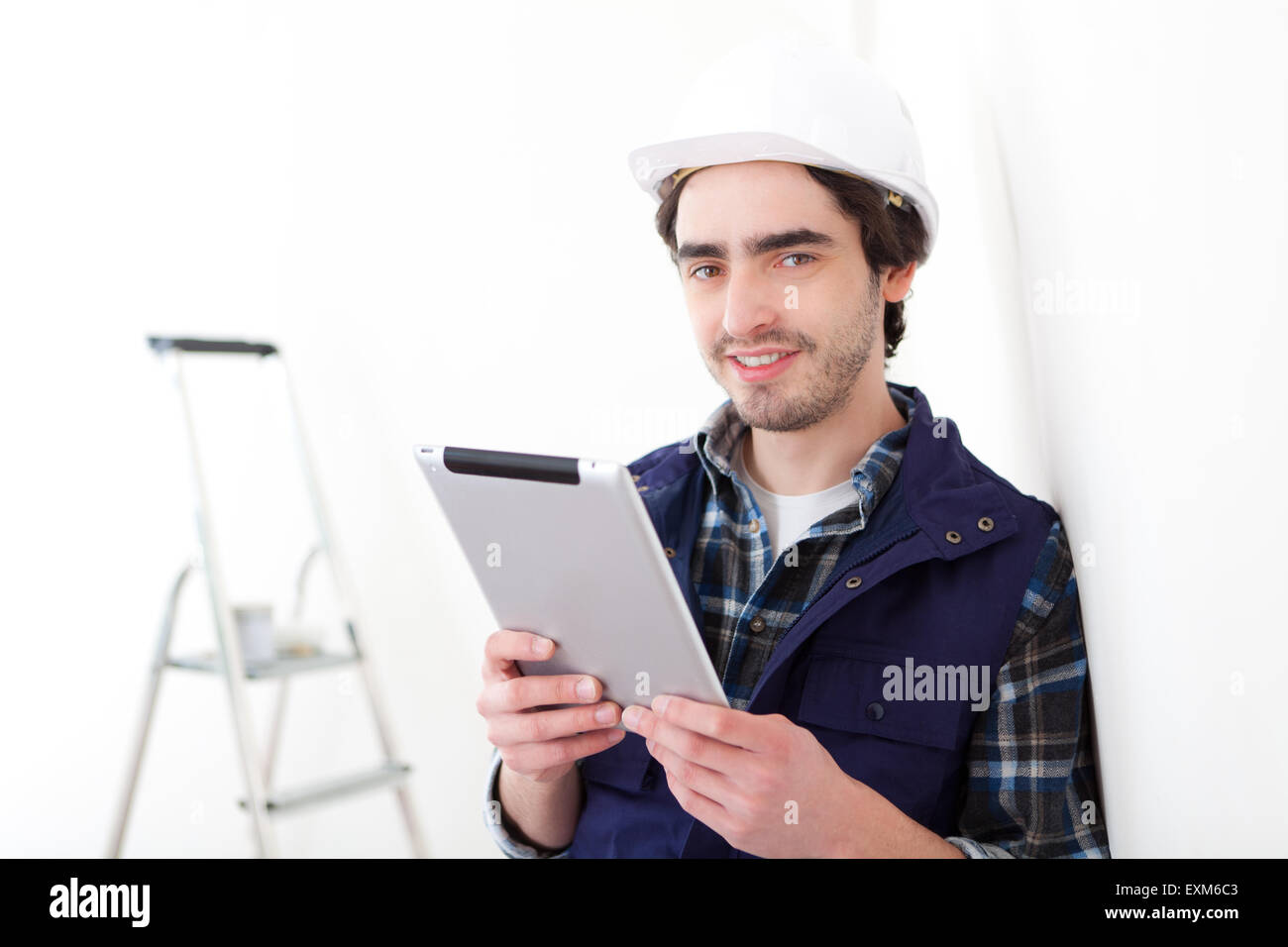 Ein junger Arbeiter Menschenbild in eine neue Wohnung mit tablet Stockfoto