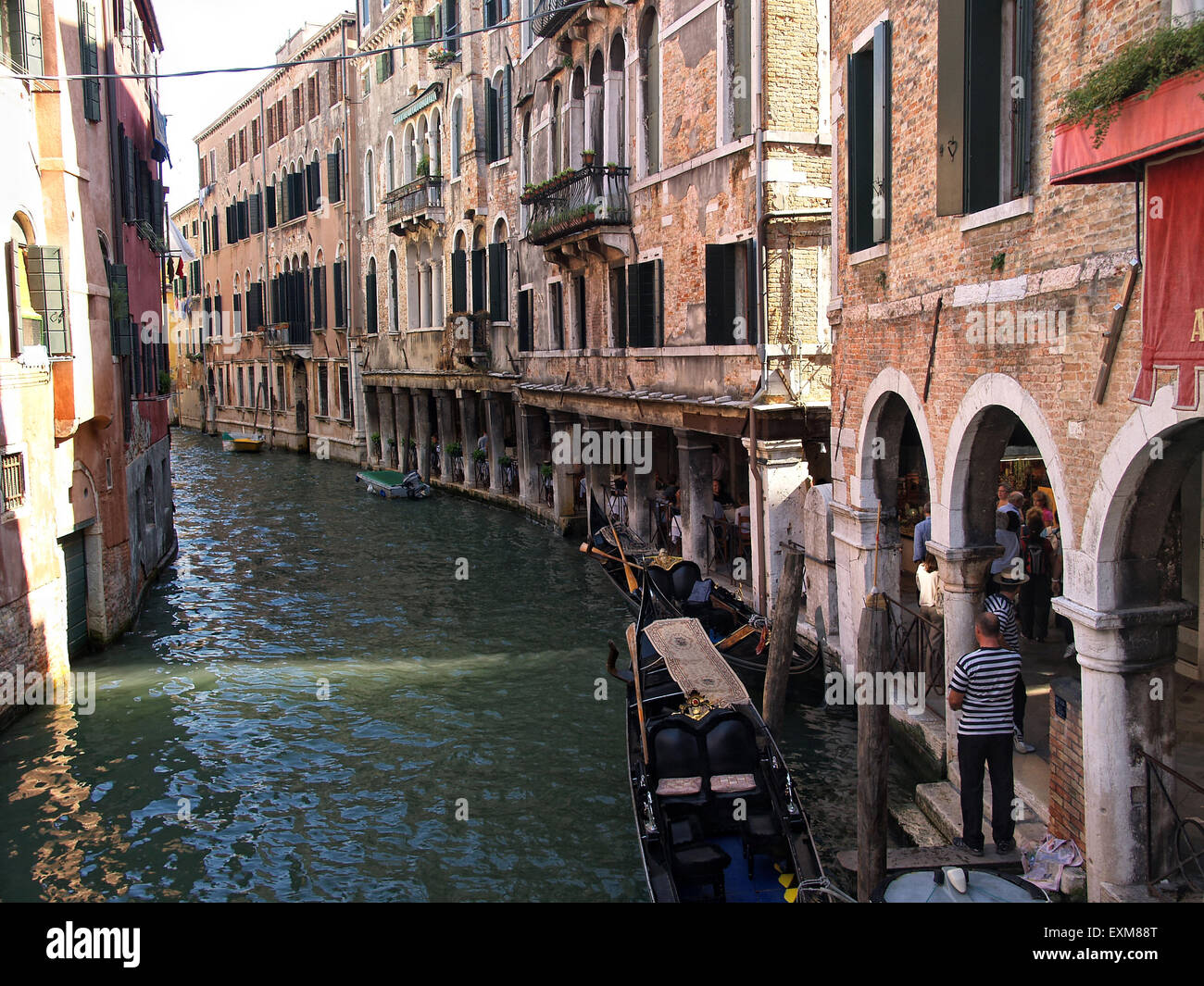 Gondel vertäut in einem schmalen Kanal mit dem Gondoliere warten auf Touristen in Venedig mit schönen Häusern an den Seiten. Venedig. Italien. Stockfoto