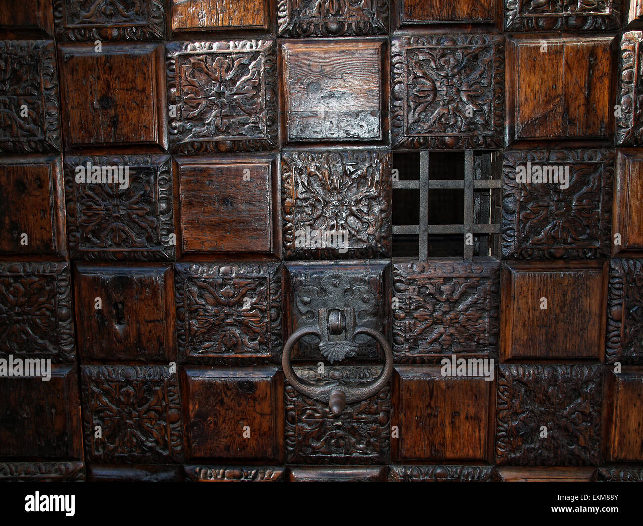 Detail einer geschnitzten Holztür mit kleinen Metall Guckloch und ein Türklopfer. Stockfoto