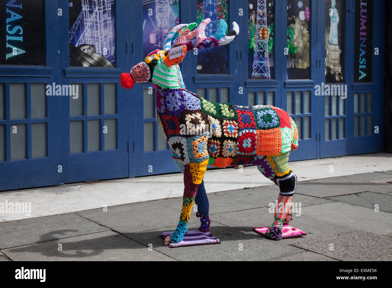 Verzierte, mit Draht gerahmte Wollhirsche, mit gehäkelten Wollquadraten aus verschiedenen Farben gestrickter Wolle bedeckte „Yarn bombed“-Anaimal. Blackpool, Großbritannien Stockfoto