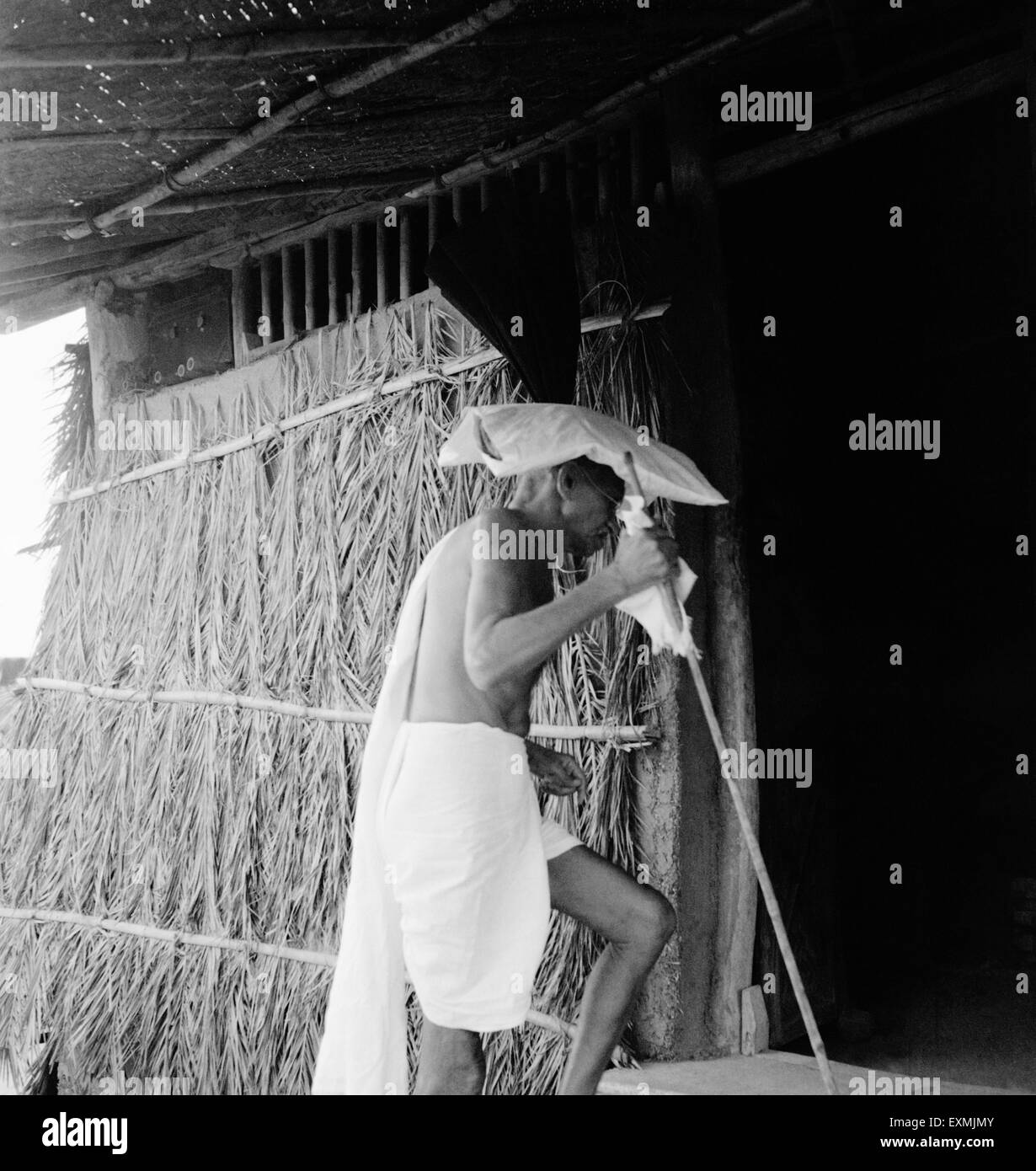 Mahatma Gandhi; tragen eine Moorpackung auf seinem Kopf; betreten eine Hütte im Sevagram Ashram; 1941 NICHT HERR Stockfoto