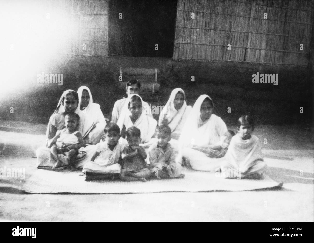 Menschen sitzen vor einer Hütte in den betroffenen Bereich von Noakhali East Bengal Aufruhr; November 1946; Indien nicht Herr Stockfoto