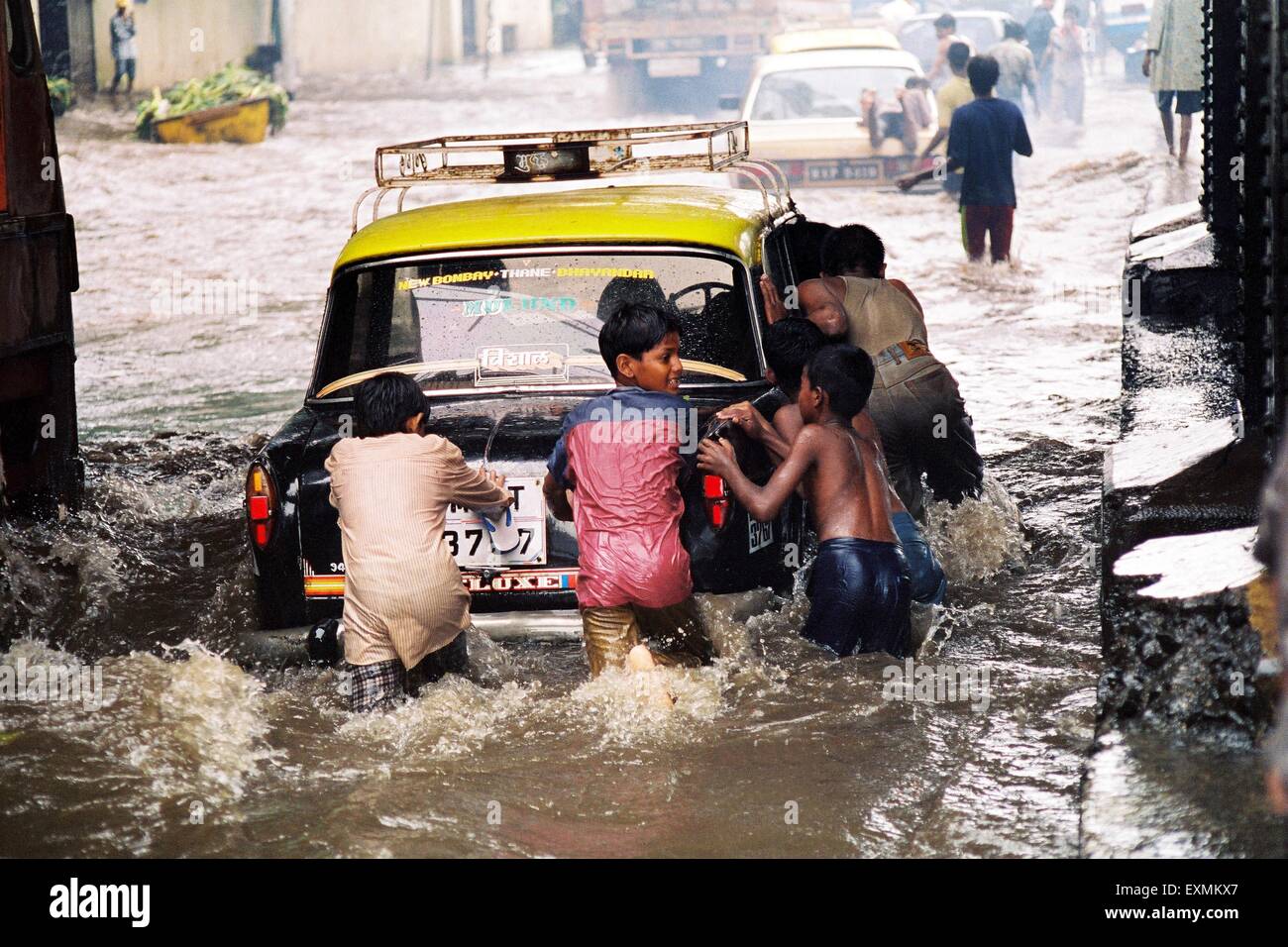 Straßenkinder drücken ein Taxi gestrandet in den überfluteten Gewässern durch heftige Regenfälle am König Circle in Bombay jetzt Mumbai Stockfoto