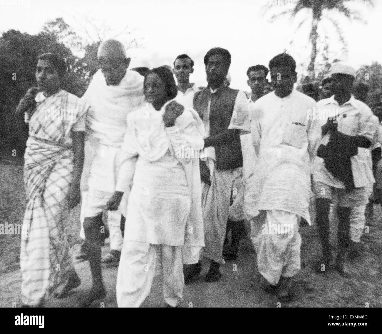 Mahatma Gandhi unterstützt Amtus Salam eine andere Frau; ein Spaziergang mit anderen durch Aufruhr bewirkt Noakhali East Bengal Stockfoto