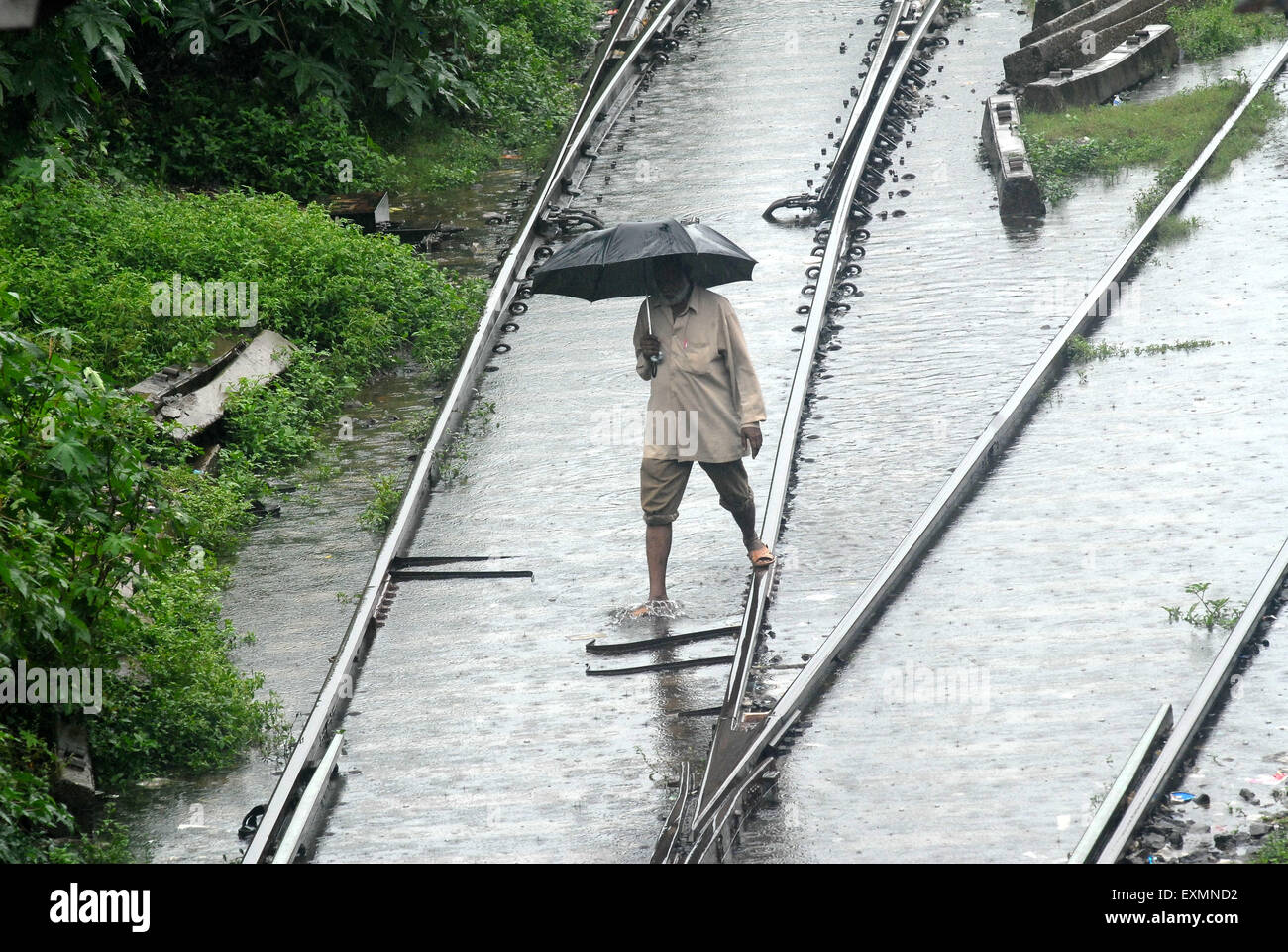 Ein Pendler Fuß in das überschwemmte Wasser auf die Bahngleise, verursacht durch starke Regenfälle in Kurla Station Mumbai Stockfoto