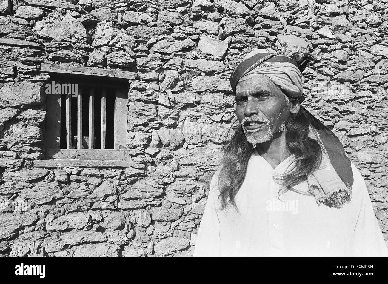 Ländliche Mann außerhalb seines Hauses Steinmauer; Lokur Dorf; Dharwar Bezirk; Bijapur Bezirk; Karnataka; Indien Stockfoto