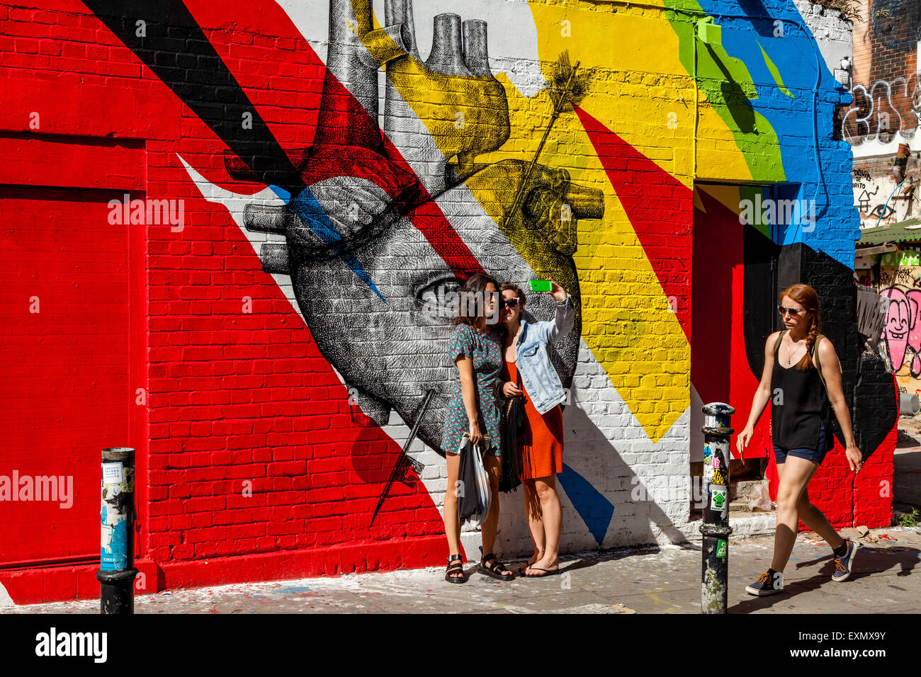 Junge Frauen posieren für A Selfie vor einige Street Art/Graffiti, Brick Lane, London, England Stockfoto