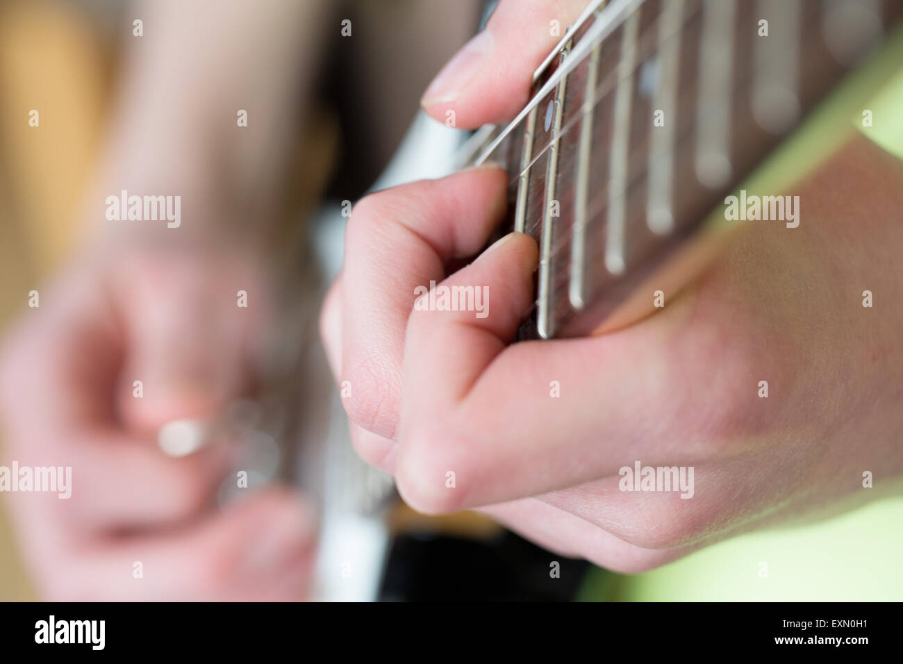 Eine Nahaufnahme von einen Akkord, der auf einer E-Gitarre Griffbrett gespielt wird. Der Gitarrist ist unscharf, kann aber nur mit einem plektrum gesehen werden. Stockfoto