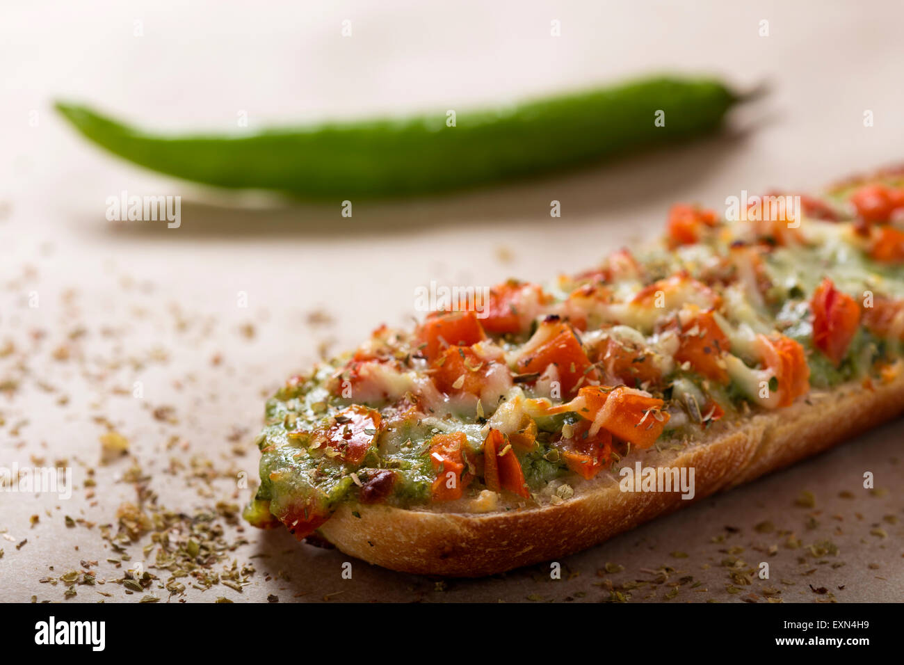 Nahaufnahme von Baguette mit Pesto und eine scharfe Paprika im Hintergrund Stockfoto