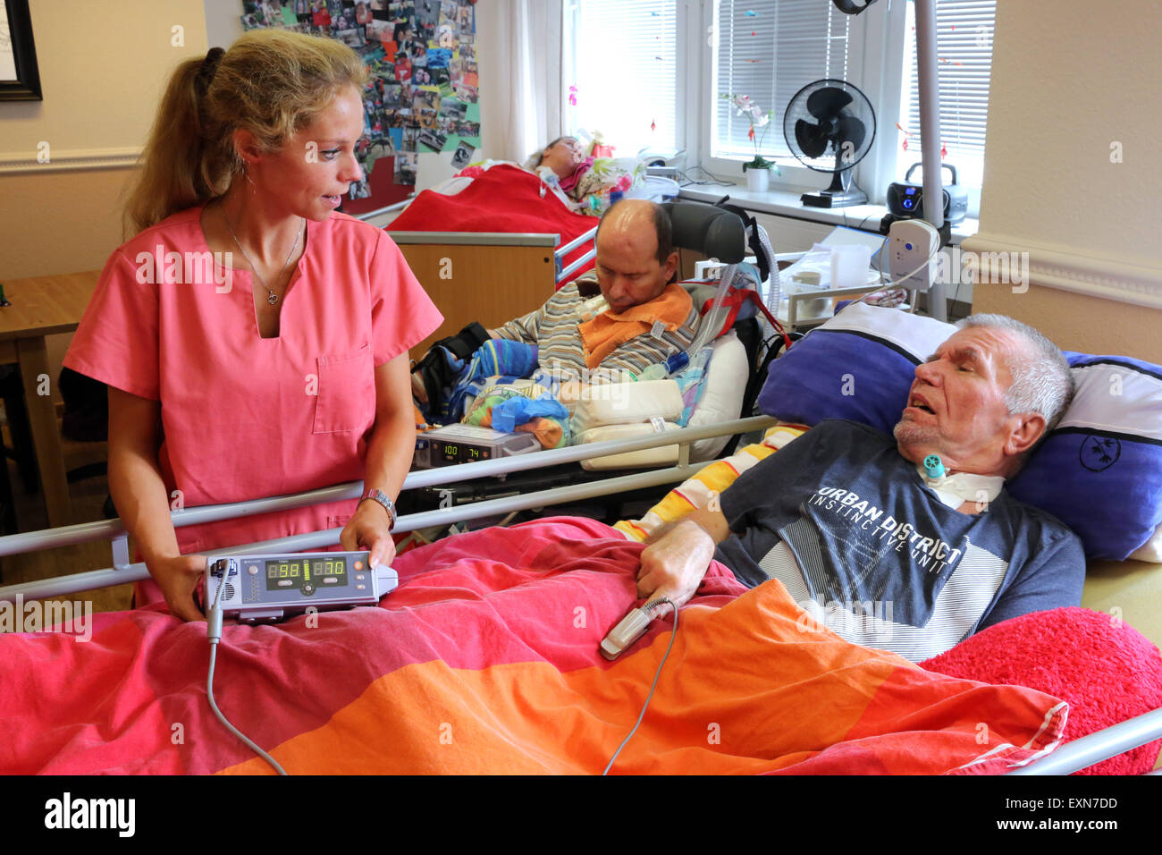 Eine Krankenschwester im Gespräch mit einem Patienten in eine künstliche Beatmung-Einheit in einem Pflegeheim in Essen/Deutschland hält eine Pulsoxymeter, Patienten zu überwachen. Stockfoto