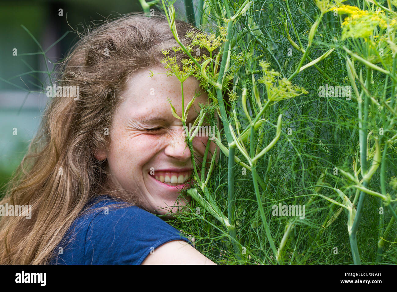 Porträt der jungen Frau mit geschlossenen Augen umarmen blühende Pflanze Stockfoto