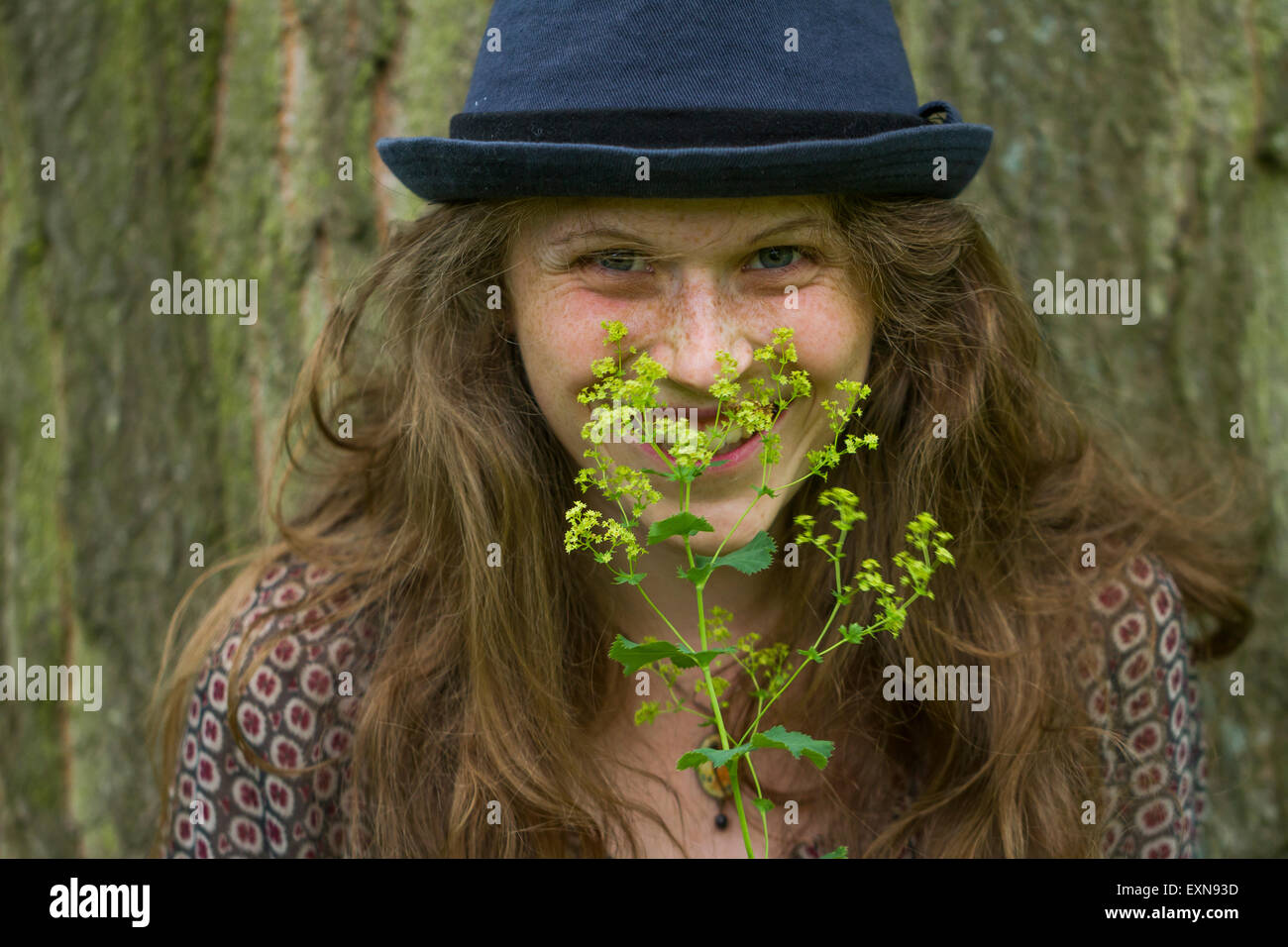 Porträt der lächelnde junge Frau mit Hut und blühender Zweig Stockfoto