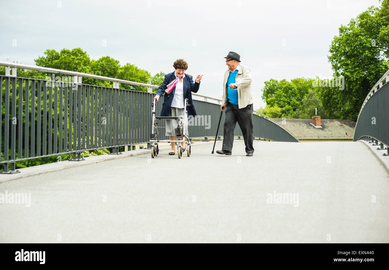 Älteres Paar mit Gehstock und Rädern Walker auf einer Brücke Stockfoto