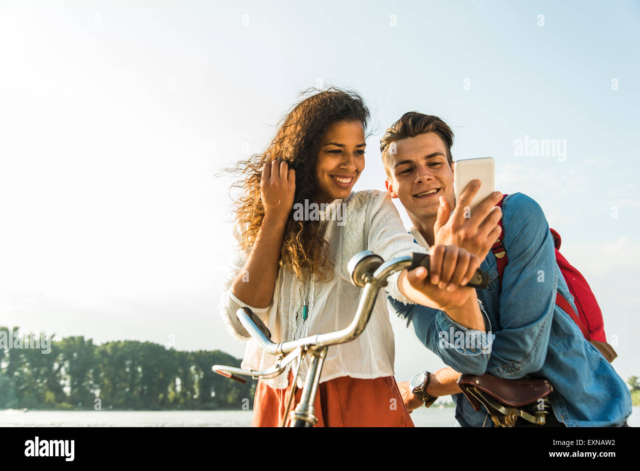 Lächelnde junge Paar mit dem Fahrrad und Handy Stockfoto