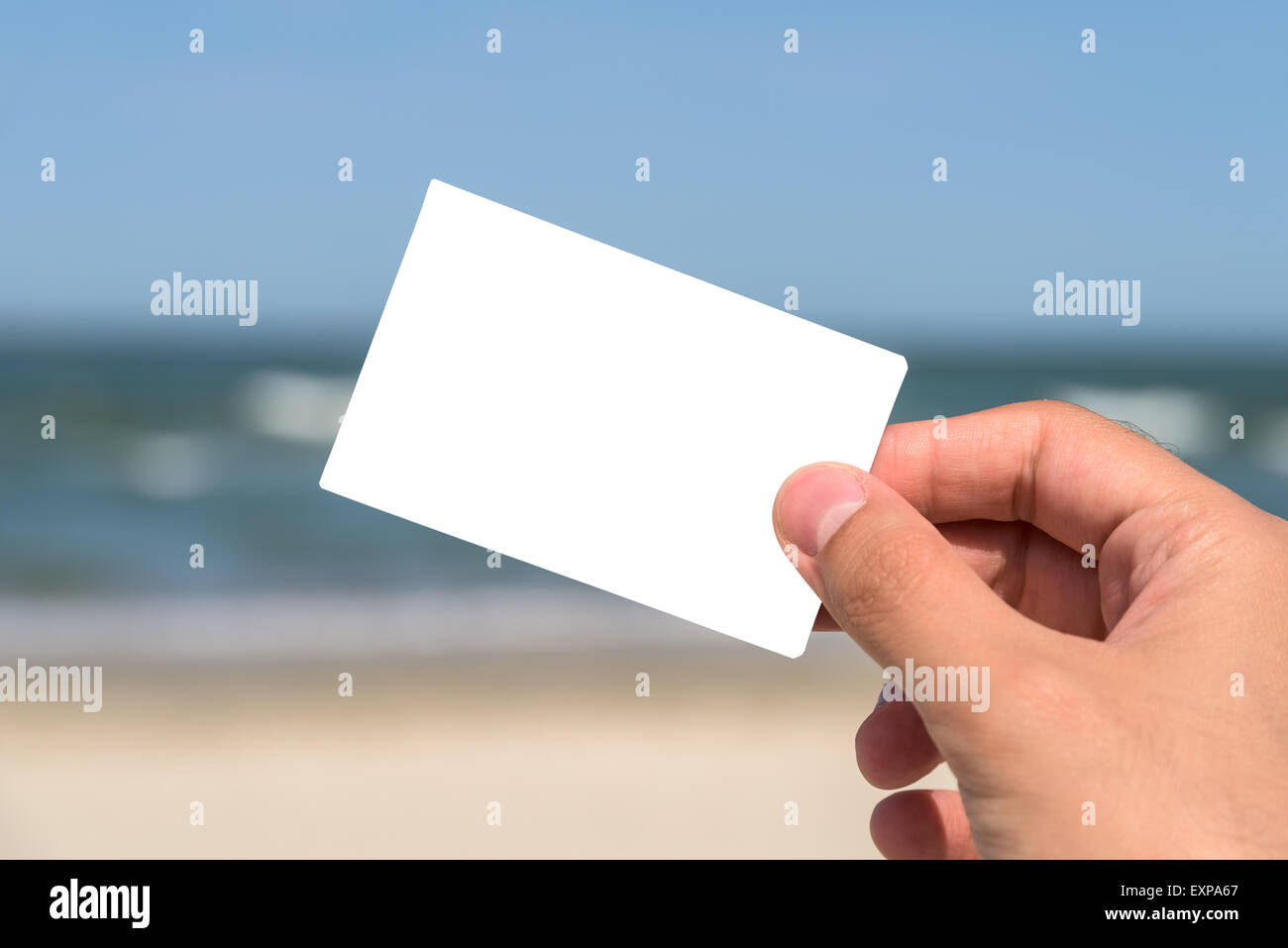 Mann Hand hielt leere weiße Karte am Strand im Sommer Stockfoto