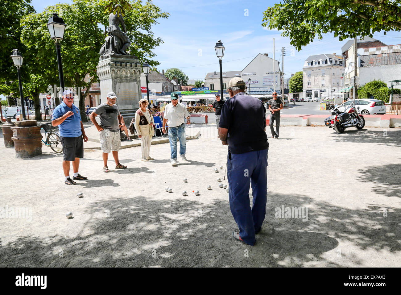Menschen spielen die typicalFrench Partie Boule im Schatten der Statue von Jeanne d'Arc in Le Crotoy Stockfoto