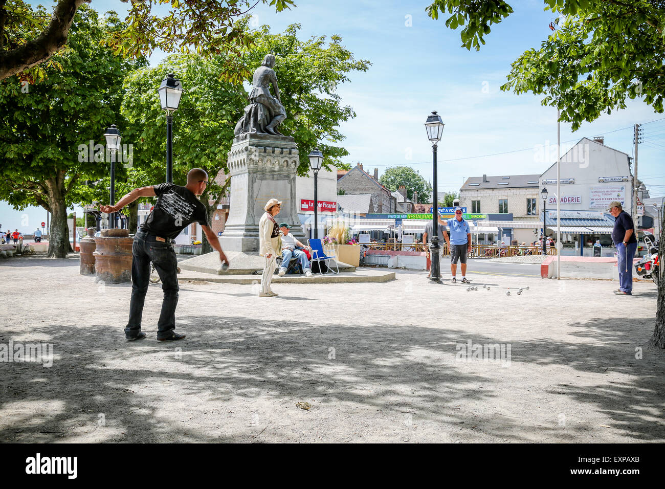 Menschen spielen die typicalFrench Partie Boule im Schatten der Statue von Jeanne d'Arc in Le Crotoy Stockfoto