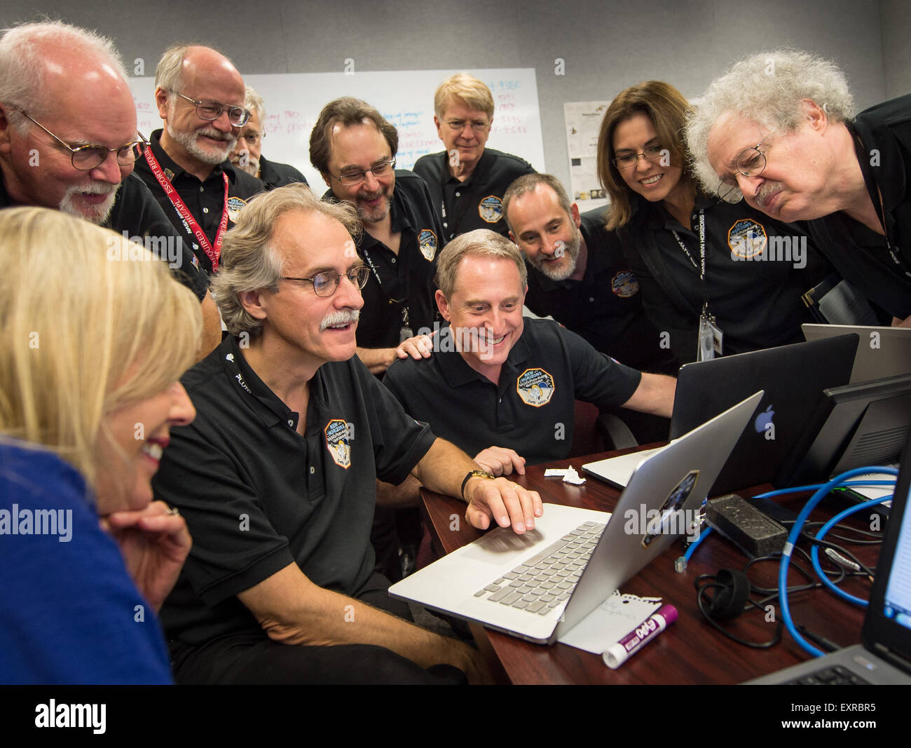 Mitglieder des Teams New Horizons versammeln sich um einen Laptop und Lächeln, als sie neu bearbeiteten Bilder von der New Horizons Raumsonde an der Johns Hopkins University Applied Physics Laboratory 15. Juli 2015 in Laurel, Maryland überprüfen. Stockfoto