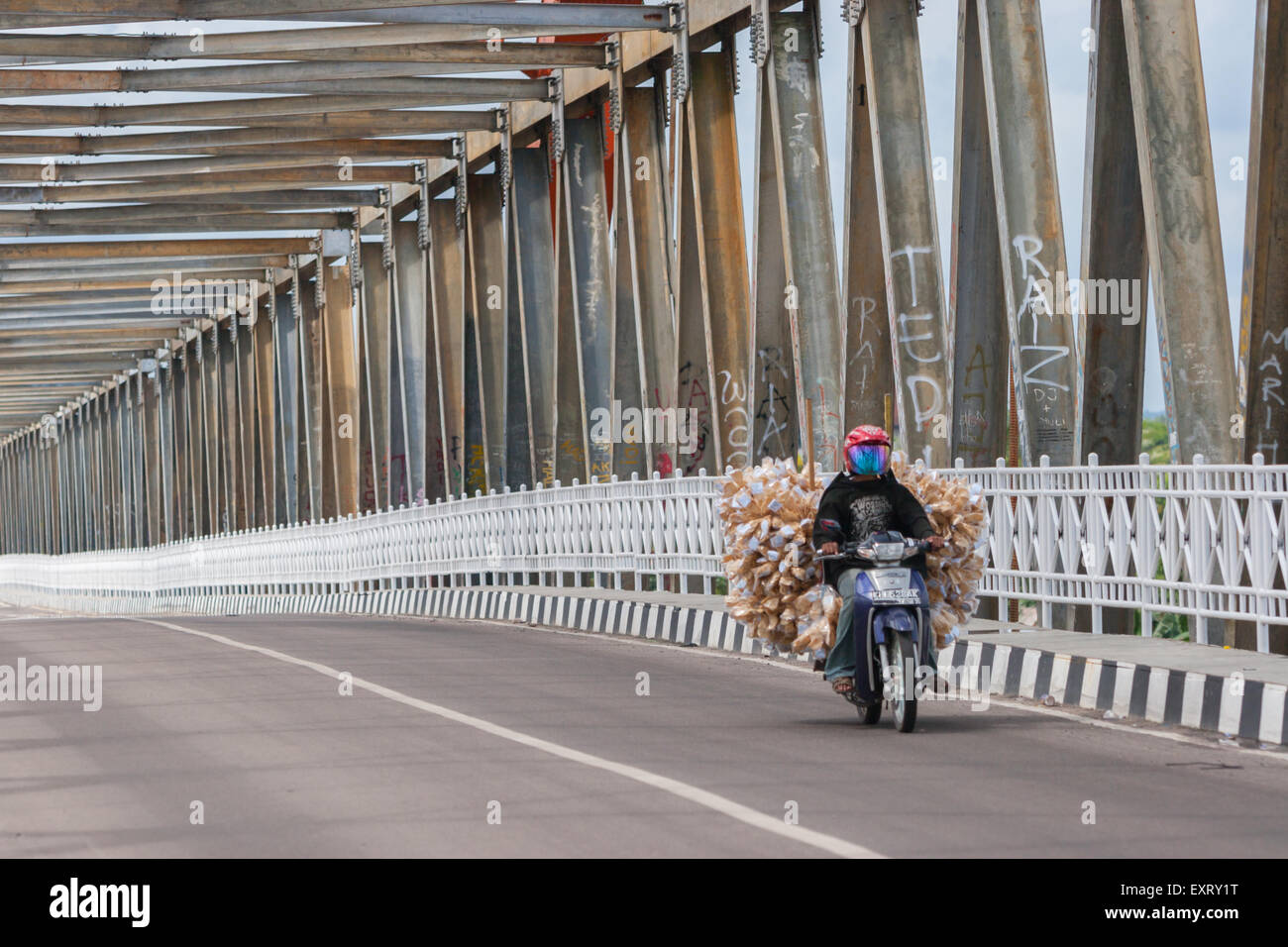 Motorradfahrer, die durch die Kahayan-Brücke fahren und Ladungen in Palangkaraya, Zentral-Kalimantan, Indonesien tragen. Stockfoto