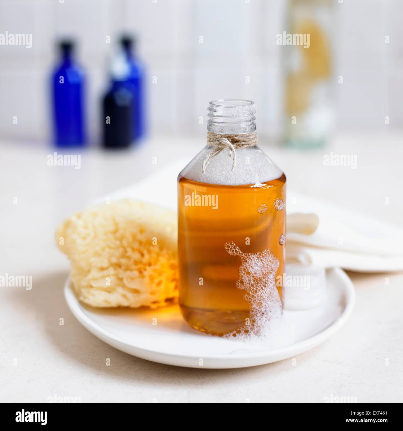 Flasche Haar Tonikum enthält getrocknete Beinwell, Calendula und Schachtelhalm, auf einem Teller, mit einem Schwamm Stockfoto
