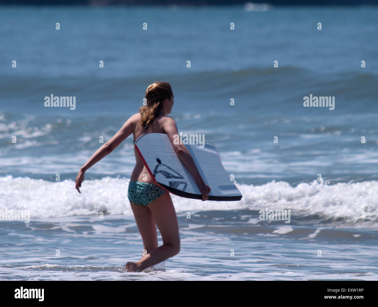 Teenager-Mädchen gehen in das Meer mit einem Bodyboard, Woolacombe, Devon, UK Stockfoto
