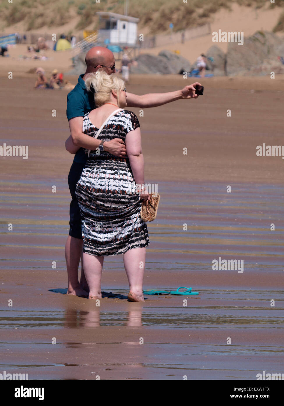 Applying paar unter einem Selfie am Strand, Woolacombe, Devon, UK Stockfoto