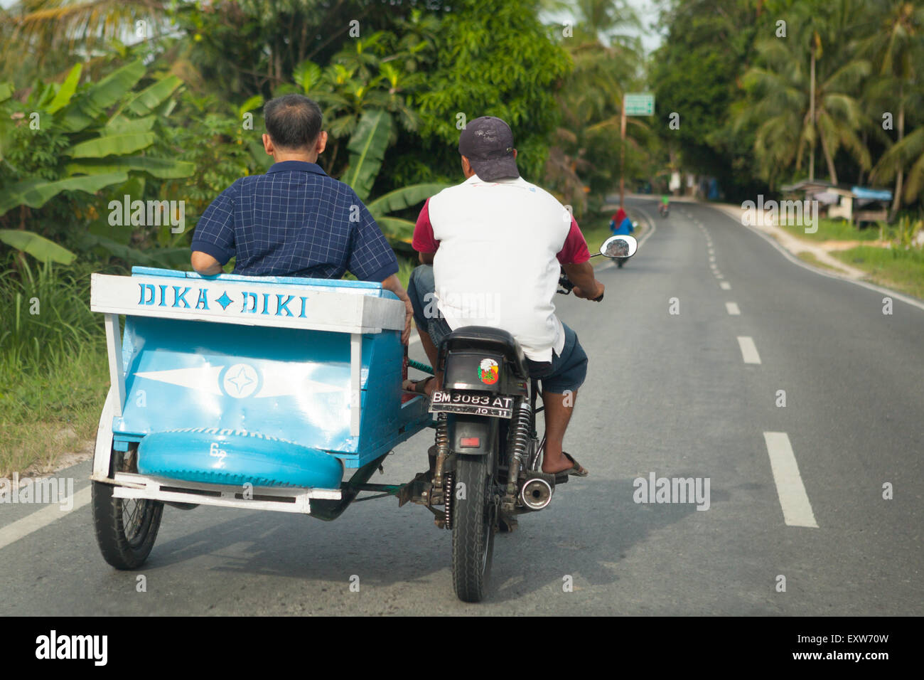 Ein Autofahrer befördert einen Passagier auf einem Motorrad mit Beiwagen, während er auf einer Straße am Stadtrand von Pekanbaru in Riau, Indonesien, fährt. Stockfoto