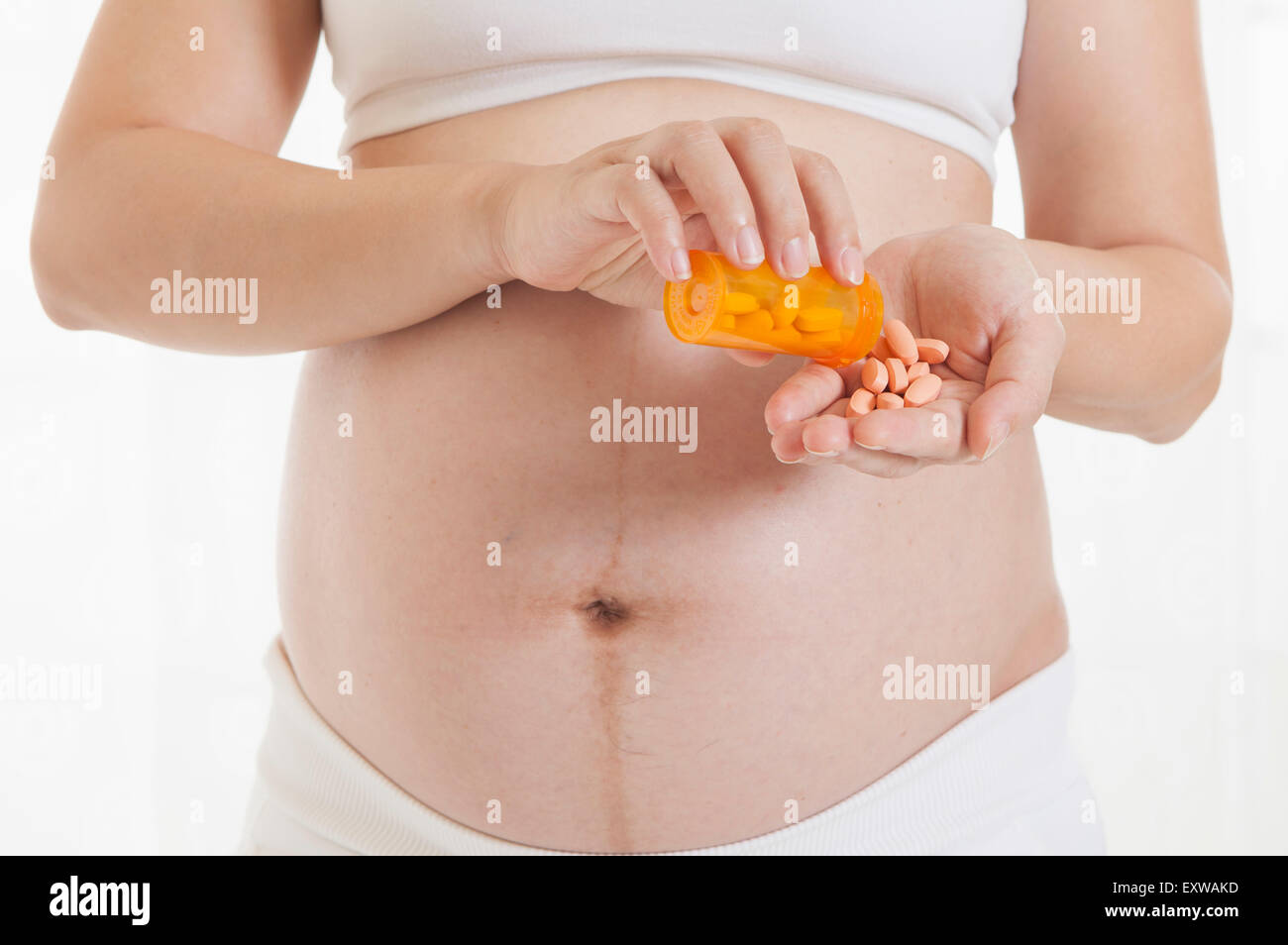 Schwangere Frau Holding Pillen und stehend, Stockfoto