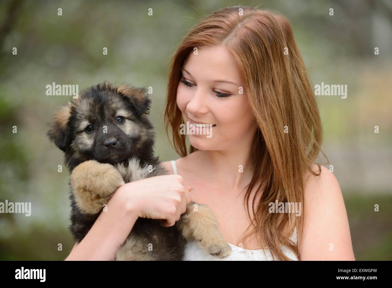 Junge Frau mit einem Mischling Hund Welpen im Garten Stockfoto