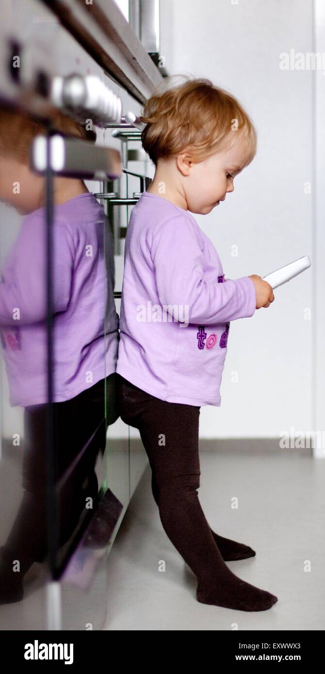 Mädchen steht mit einem schnurlosen Telefon am Elektroherd Stockfoto