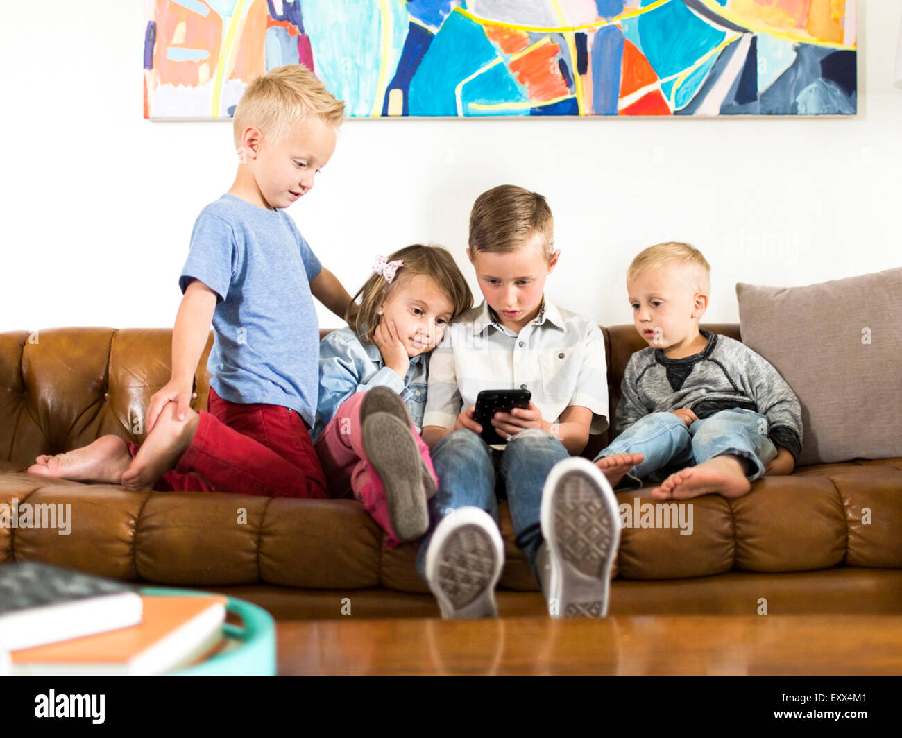 Kinder (2-3, 4-5, 6-7) auf Sofa sitzen und mit smartphone Stockfoto