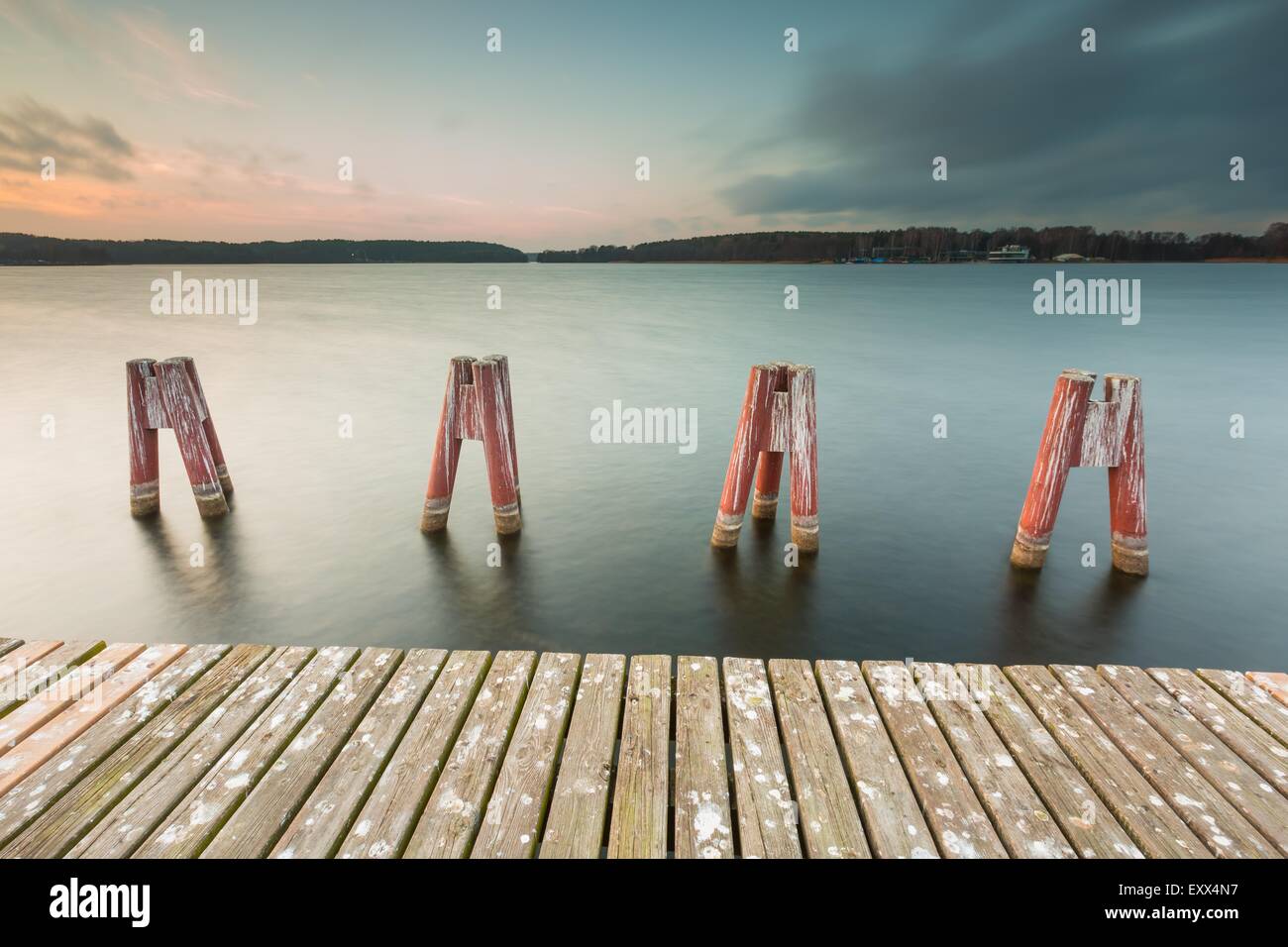 Schöne Seenlandschaft mit Steg. Langzeitbelichtung Fotos mit Filter. Polnische Seeufer bei bewölktem Wetter Sonnenuntergang. Dramatische Stockfoto