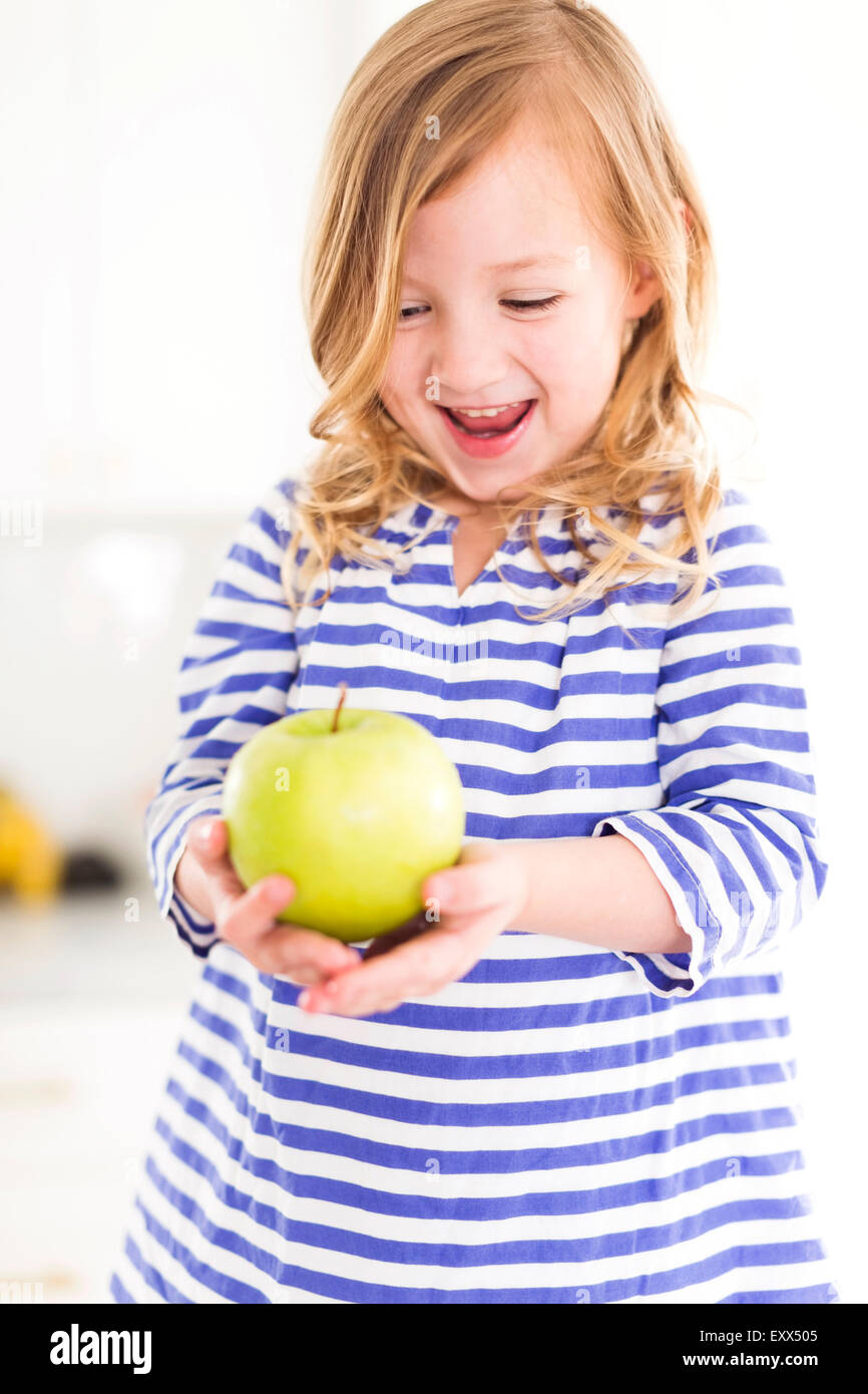 Mädchen (4-5) Blick auf Äpfel, lachen Stockfoto
