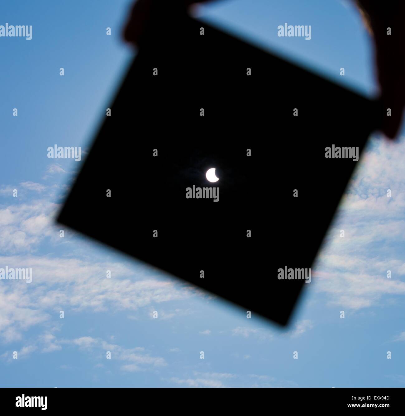 Partielle Sonnenfinsternis. Manndeckung einen starken Sonneneinstrahlung durch dunkle Platte und Sonnenfinsternis zeigt. Mann Hand Silhouette am blauen Himmel. Stockfoto