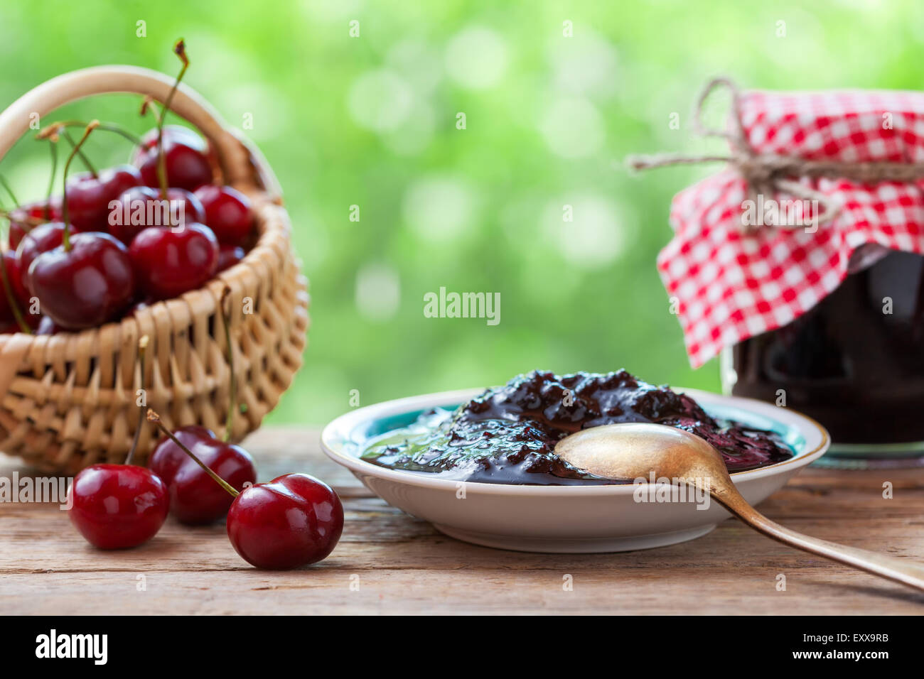 Korb mit Kirsche, Untertasse und Glas Marmelade. Stockfoto